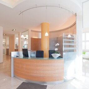 Heller Empfangsbereich einer modernen Zahnarztpraxis mit Wartebereich und Pflanzen.