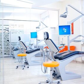 Moderne Zahnarztpraxis mit Behandlungsstuhl, Monitoren und heller, hygienischer Ausstattung.