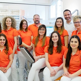 Das Praxisteam einer Zahnarztpraxis steht gemeinsam in moderner, heller Umgebung.